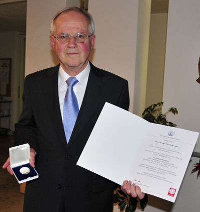 Mann zeigt Medaille und Urkunde